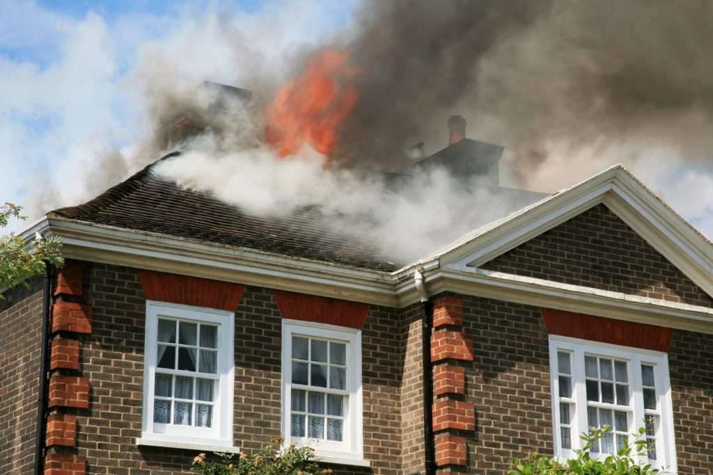 Fire damage at a house with smoke and flames coming from the roof